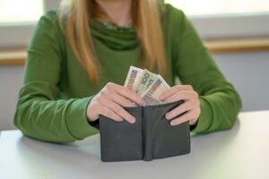 A woman sits at a table, withdrawing money from her wallet, reflecting on a recent medical malpractice settlement.