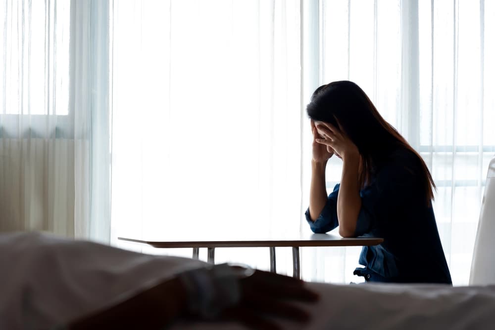 Woman looking concerned at her friend in the hospital bed, representing medical treatment, healthcare, family, and love.