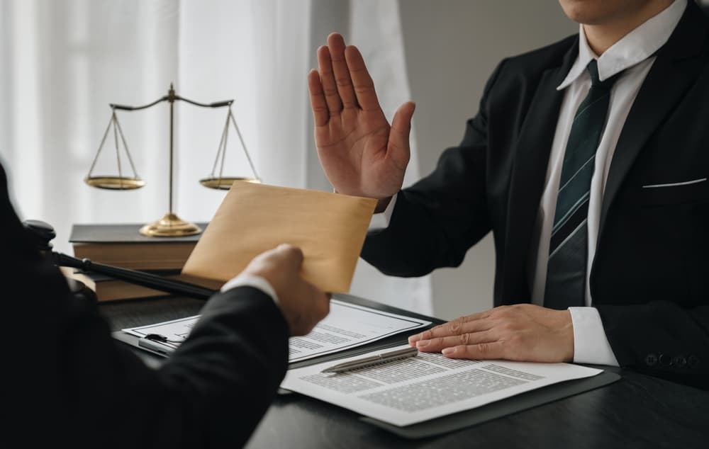 Lawyer refusing a document with a hand gesture, scales of justice visible.