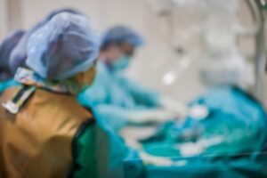 Blurred image of a modern Cath Lab with medical professionals and patient undergoing treatment in a hospital setting.