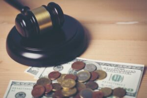 Close-up of a legal court gavel resting on assorted cash, symbolizing financial implications and justice in legal matters.