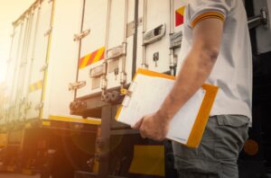 image of a truck accident investigator examining a collision scene, taking notes, and inspecting the damaged vehicles.