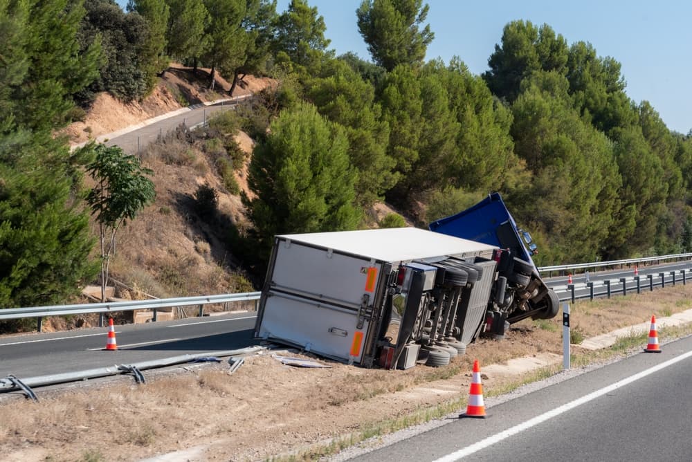 A refrigerated semi-trailer truck overturned in the median after exiting the highway.