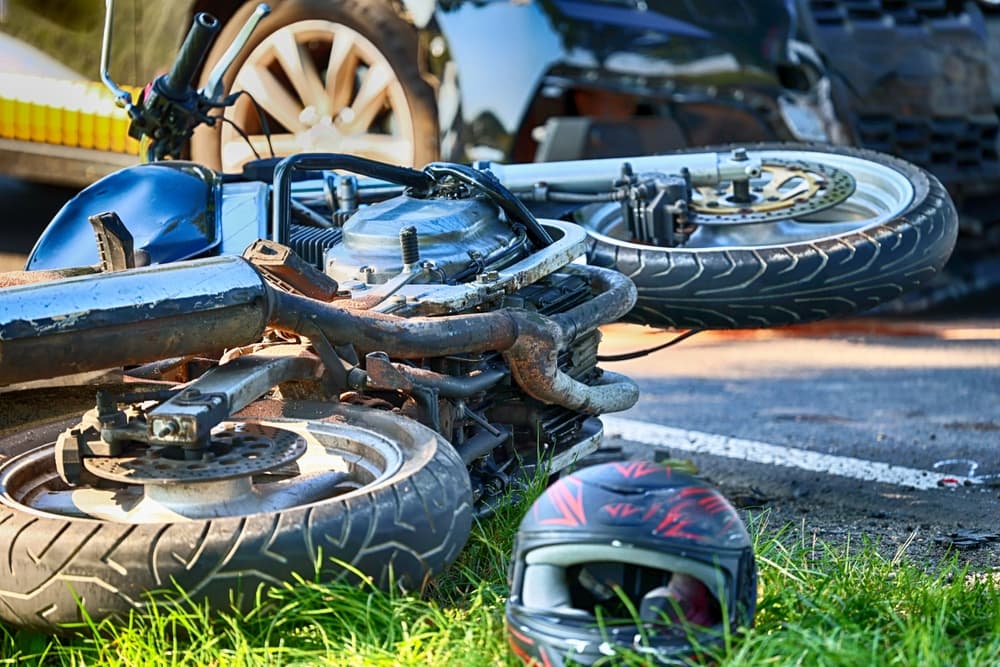 A crashed motorcycle lying on the road with a helmet nearby, after an accident.