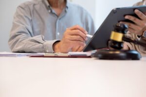 A personal injury lawyer reviewing documents on a tablet, with a gavel on the table, symbolizing legal consultation.