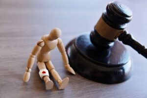 A wooden figure with an injury sits beside a gavel, symbolizing choosing a personal injury lawyer.