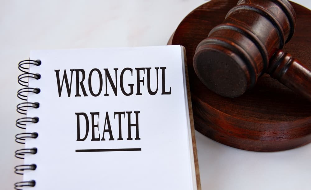 A notepad with "WRONGFUL DEATH" written on it beside a judge's gavel, symbolizing legal claims.